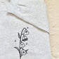A whimsical twist on a classic botanical design, the "Ghost of the Valley" crewneck features delicate Lily of the Valley blooms transformed into subtle, charming little ghosts with embroidered sparkle accents. Minimalist, fine-line stitching gives this piece an understated cottagecore feel that works effortlessly for spooky season and beyond.

    Fine-Line Machine Embroidery: Crisp, detailed black linework designed to lay flat and hold up to daily wear.

    Subtle & Aesthetic: Perfect for those who prefer