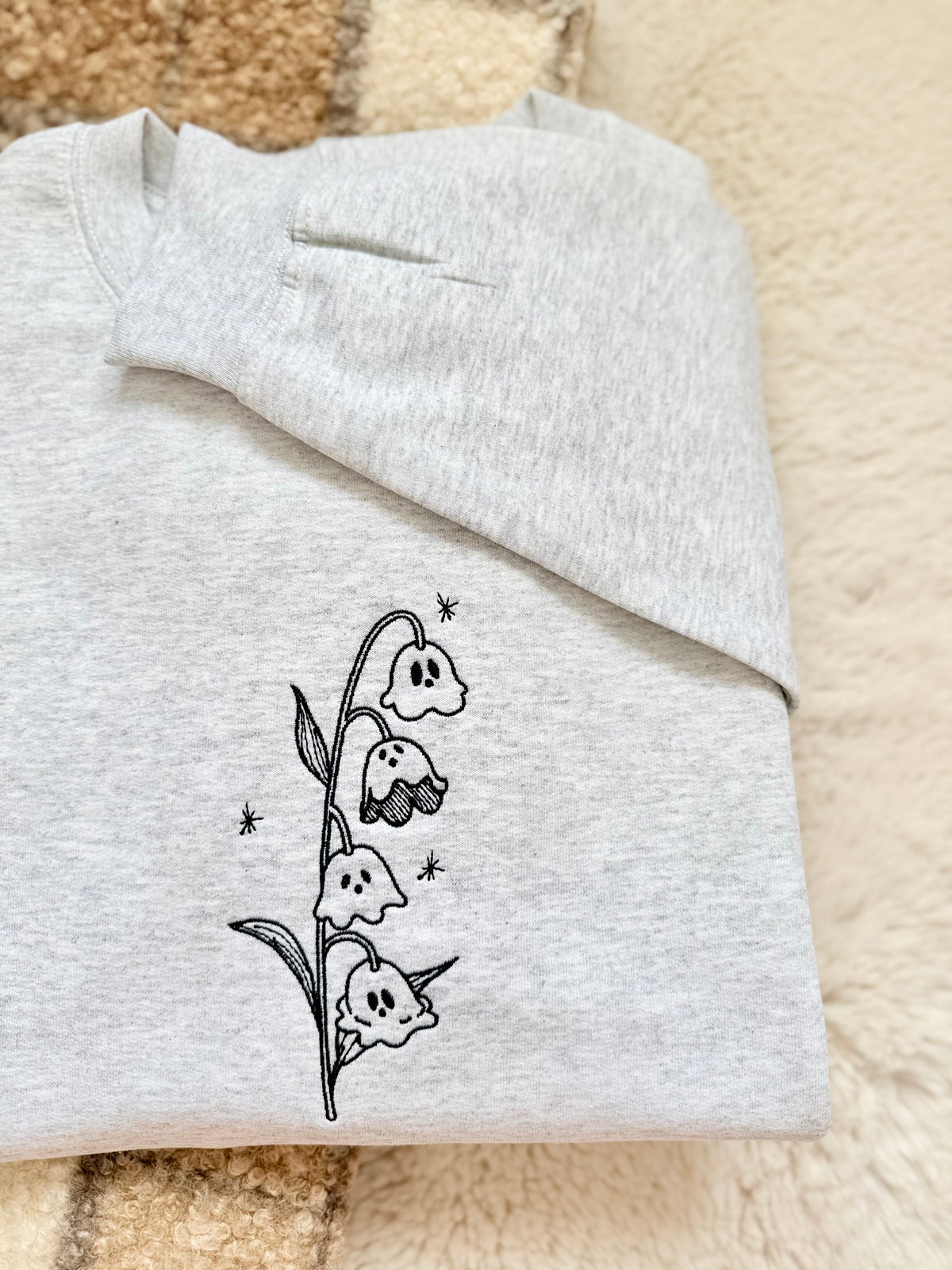 A whimsical twist on a classic botanical design, the "Ghost of the Valley" crewneck features delicate Lily of the Valley blooms transformed into subtle, charming little ghosts with embroidered sparkle accents. Minimalist, fine-line stitching gives this piece an understated cottagecore feel that works effortlessly for spooky season and beyond.

    Fine-Line Machine Embroidery: Crisp, detailed black linework designed to lay flat and hold up to daily wear.

    Subtle & Aesthetic: Perfect for those who prefer