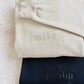 Folded beige sweatshirt with 'wifey' and navy sweatshirt with 'hubby' on a textured surface