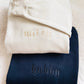 Folded white sweatshirt with 'wife' and navy sweatshirt with 'hubby' text on a textured surface.