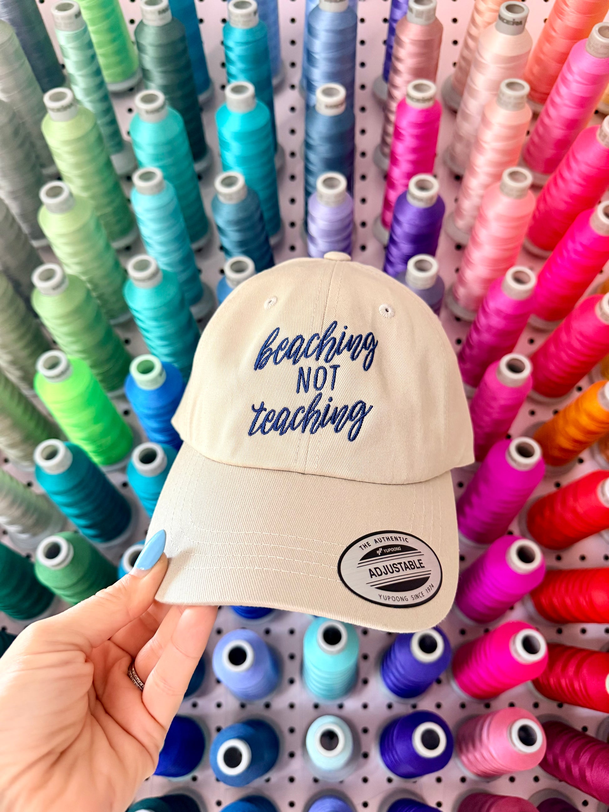 Beige cap with 'beaching not teaching' text on a white background. Embroidered custom hat stitched in Ontario, Canada. 