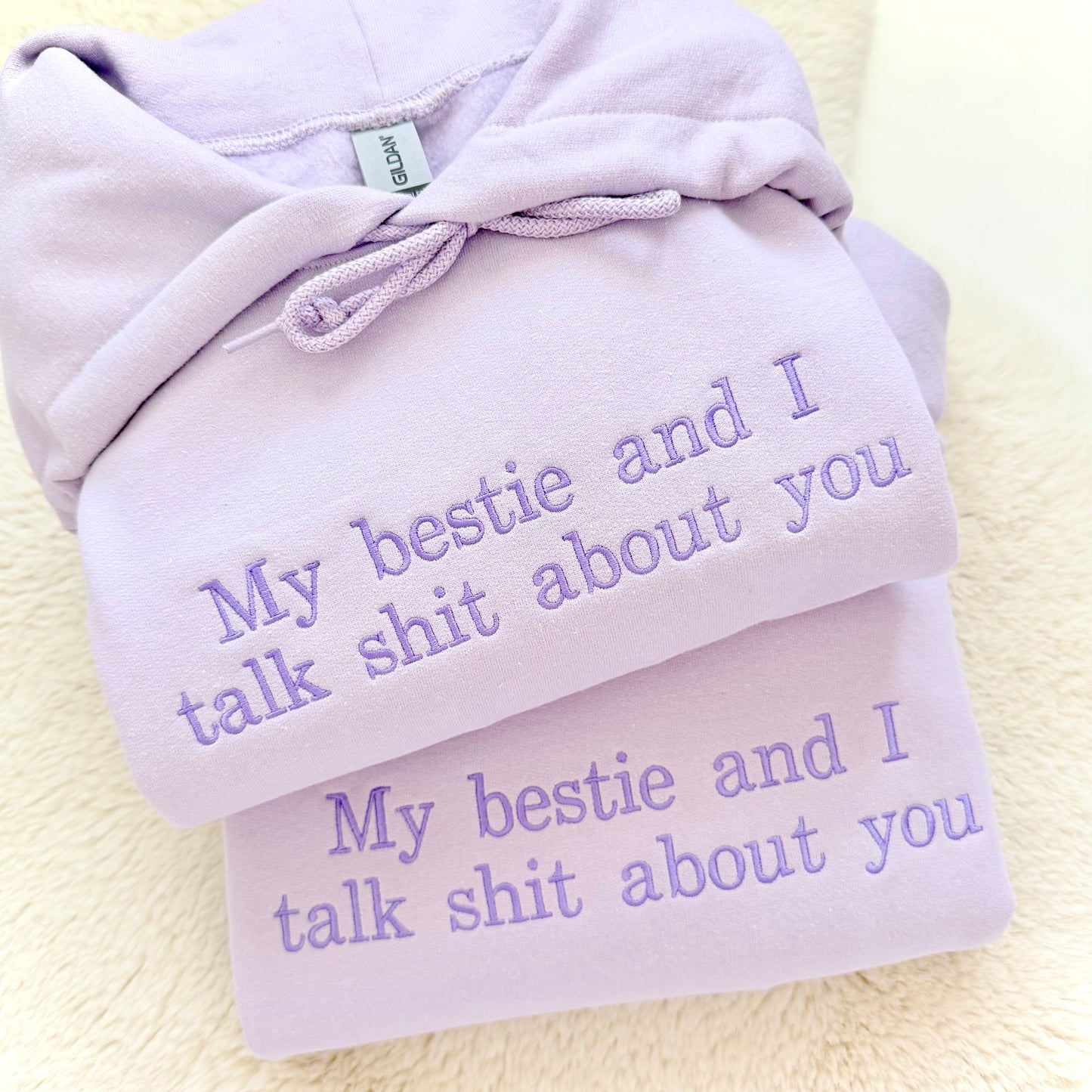 Light purple hoodie with embroidered text on a light background
