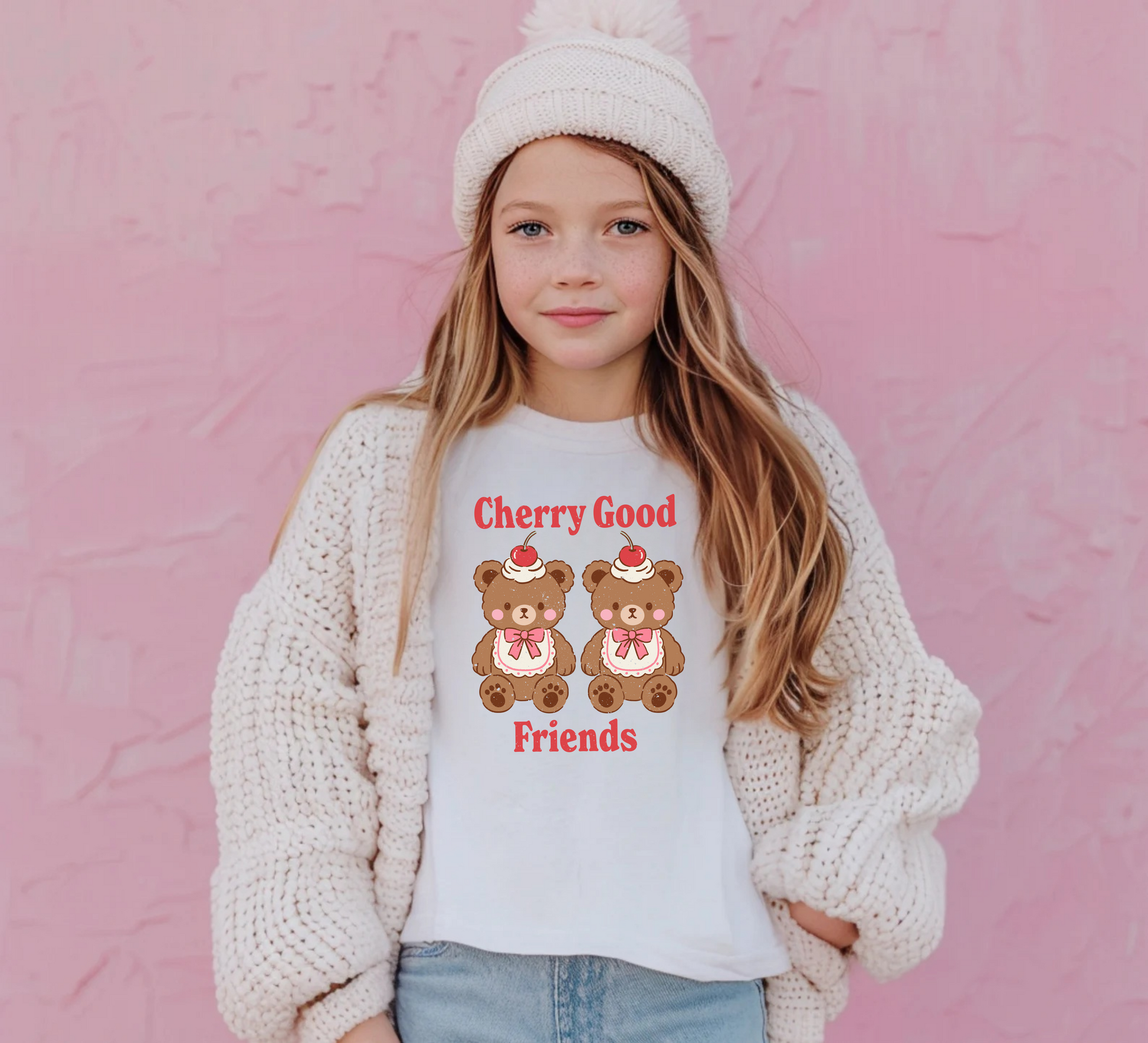 Young girl wearing a white sweater with teddy bear design and text against a pink background