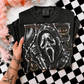 A black sequined t-shirt featuring a Ghostface graphic, held by a tattooed hand over a black and white checkered surface with pink and white faux fur props.