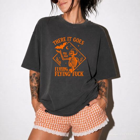 A woman wearing an oversized charcoal gray graphic t-shirt with an orange skeleton and bat design, paired with orange and white gingham shorts with a lace hem.