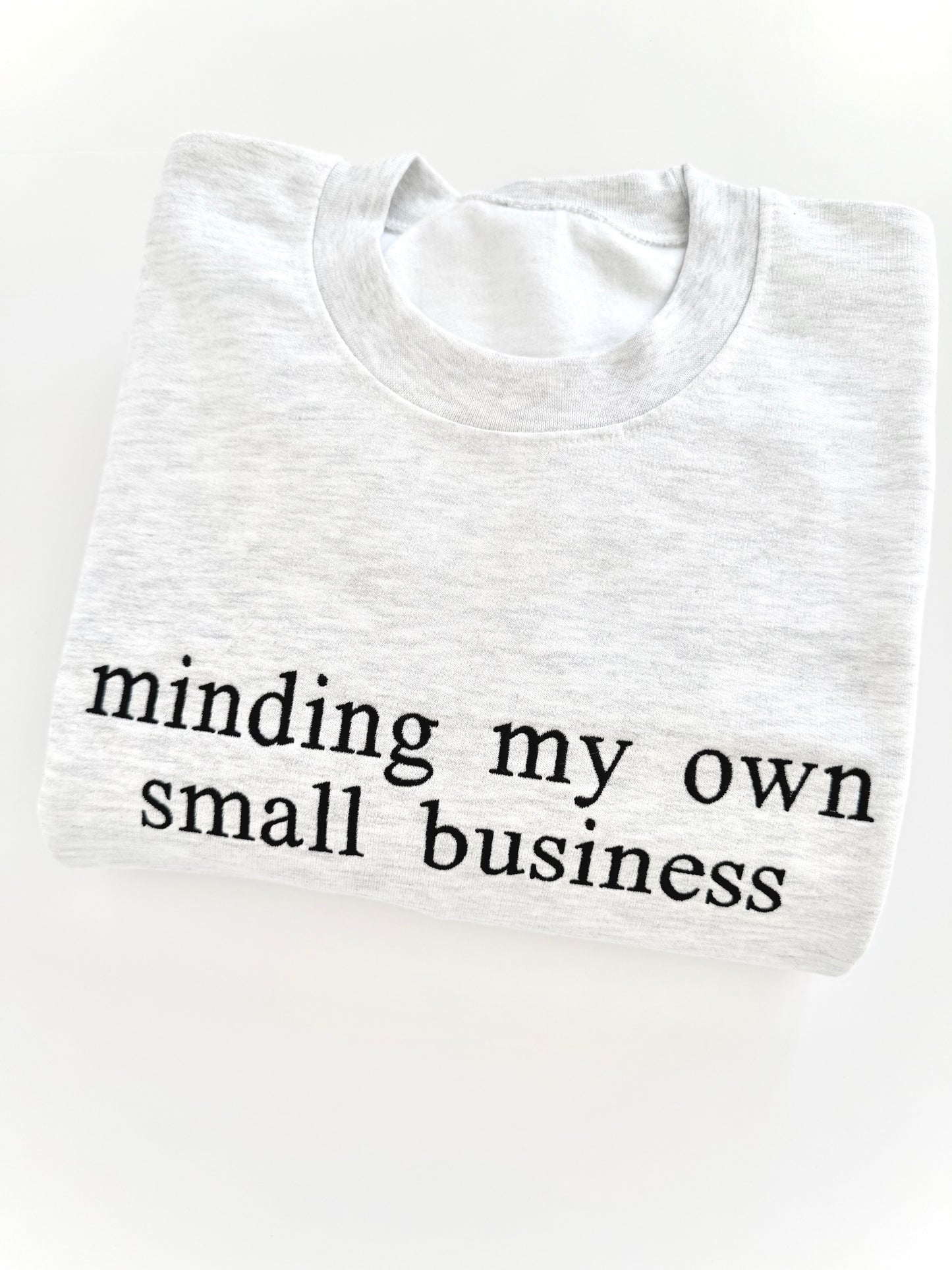 White t-shirt with 'minding my own small business' text on a white background