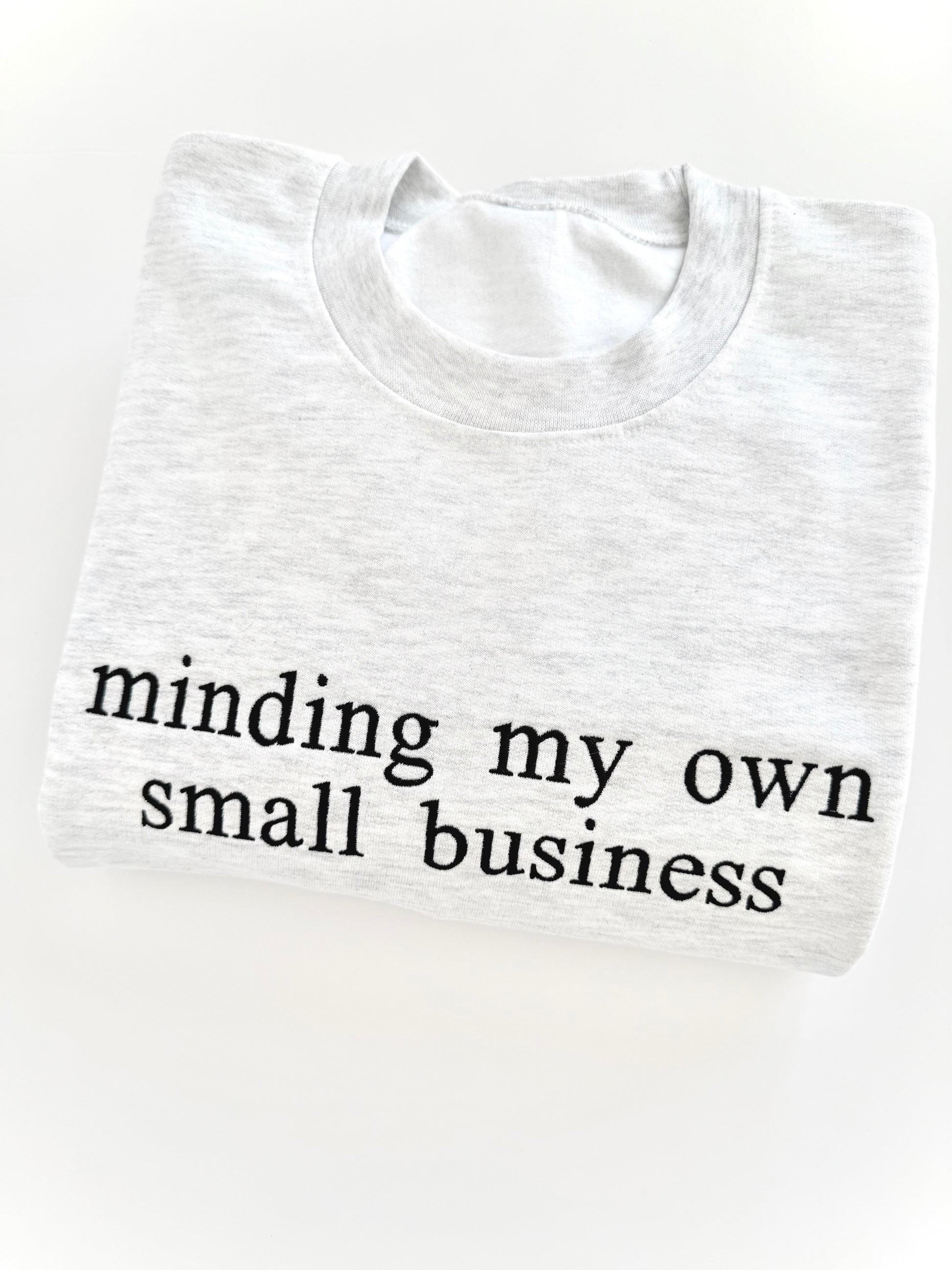 White t-shirt with 'minding my own small business' text on a white background