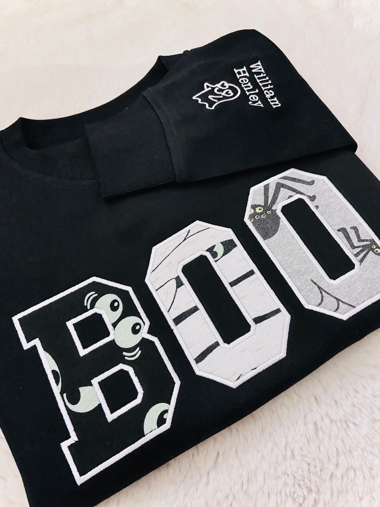 Black t-shirt with 'BOO' design and matching black cap on a light background