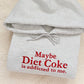Gray hoodie with red text 'Maybe Diet Coke is addicted to me.' on a beige background