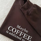 Brown sweatshirt with text 'Maybe COFFEE is addicted to me.' on a textured surface