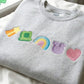 Gray sweatshirt with colorful embroidered patches on a white background